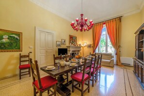 Comedor con candelabro, chimenea y vistas al exterior.