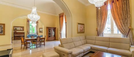 A spacious living room with a large beige sofa, a wooden coffee table, and a chandelier.