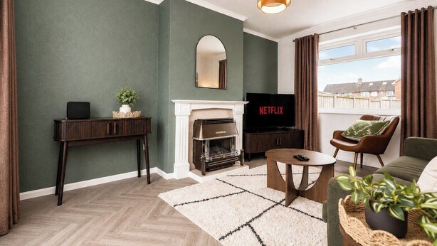 Een woonkamer met een open haard, een televisie en uitzicht op buiten.