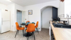 Een moderne keuken met een eethoek, witte wanden en een visgraatvloer.