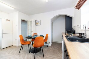 Eine moderne Küche mit Essbereich, weißen Wänden und einem Fischgrätparkett.