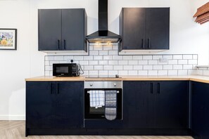 Eine moderne Küche mit dunklen Schränken, einer Mikrowelle, einem Backofen und einer gefliesten Rückwand.