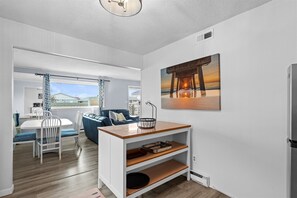 Eine moderne Küche mit einer Holzausziehtheke, weißen Schränken und einem Gemälde eines Piers an der Wand.