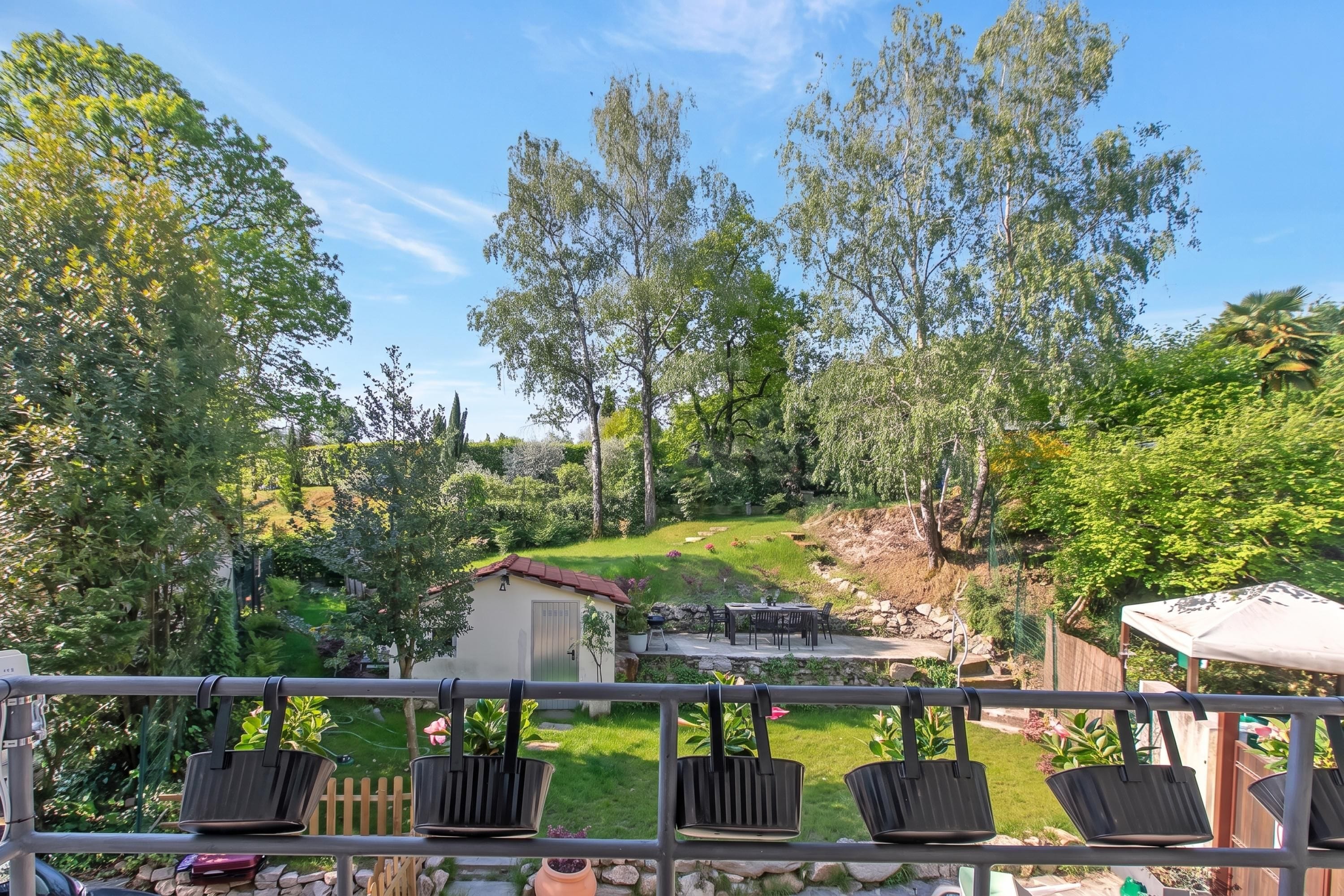 A patio with outdoor furniture, a small shed, and a grassy area with trees.