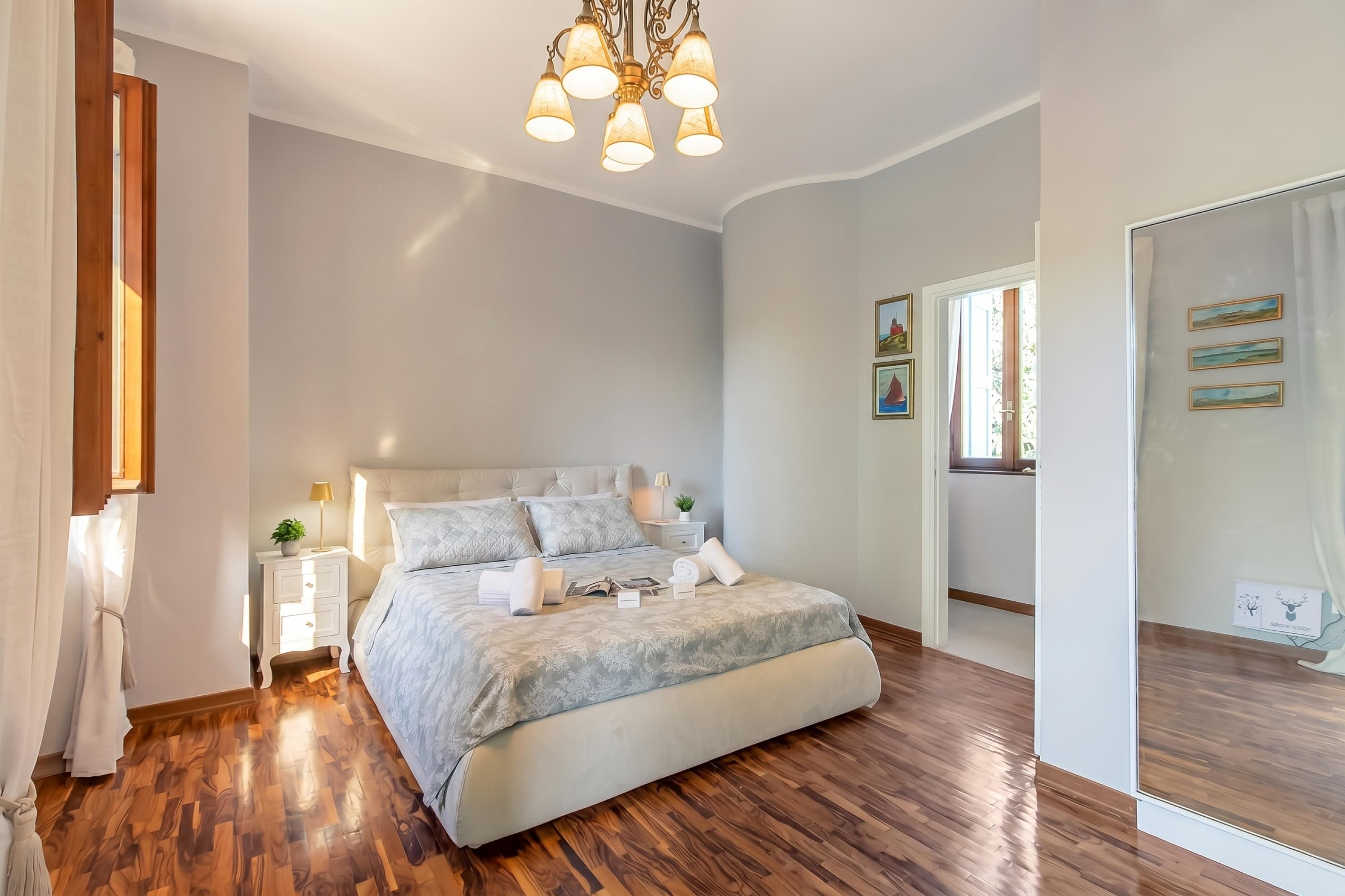 Una camera da letto con un letto grande, comodini, uno specchio e un lampadario.