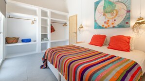 Un dormitorio con una colcha a rayas coloridas, un cuadro abstracto grande en la pared y una puerta de madera.