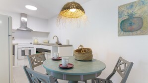 Una cocina con una mesa redonda, sillas, una lámpara colgante y un cuadro en la pared.