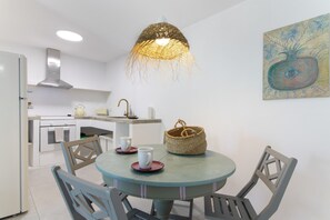 Una cocina con una mesa redonda, sillas, una lámpara colgante y un cuadro en la pared.