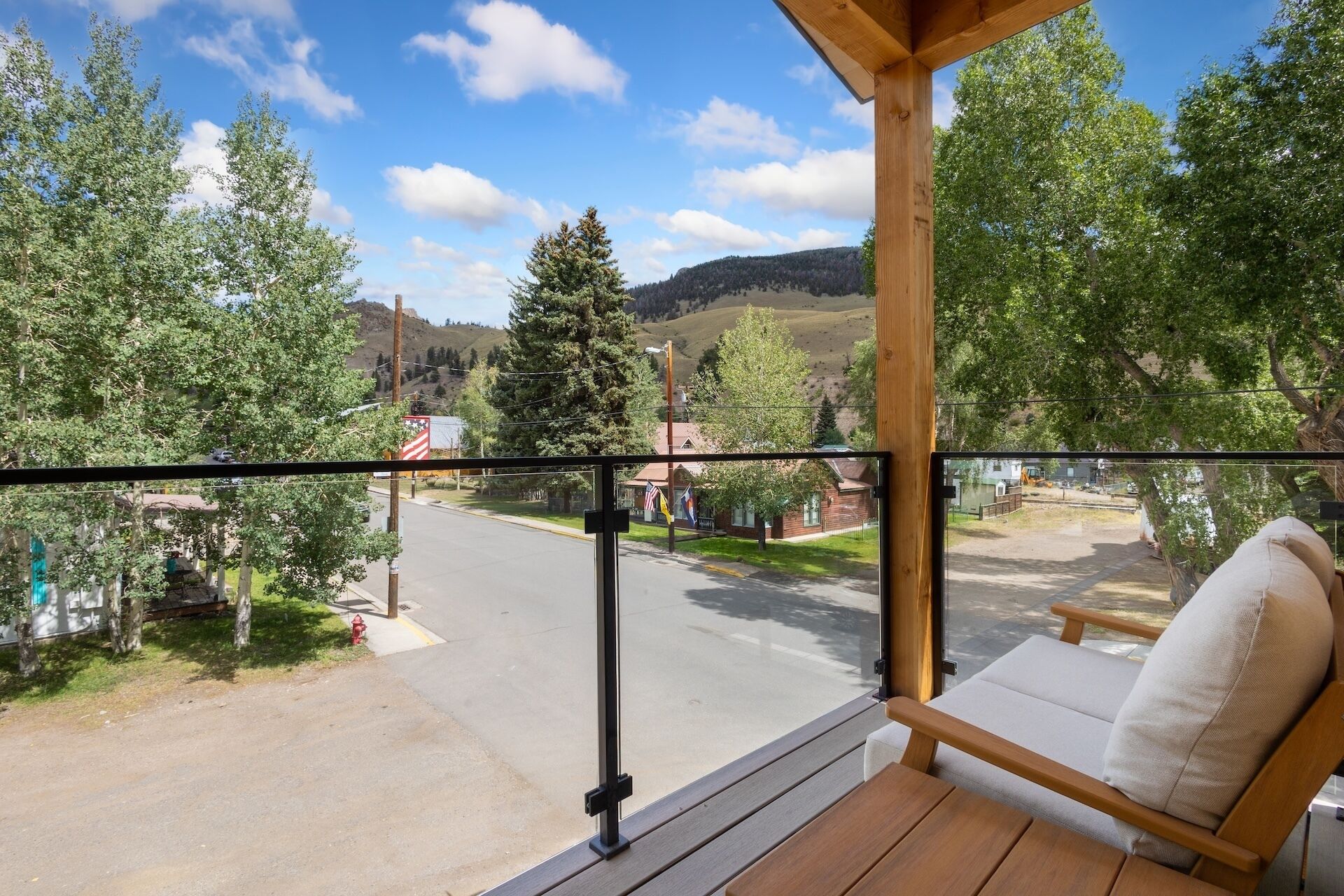 Ein Balkon mit Holzbalkon, einer Sitzbank und Blick auf eine Straße mit Gebäuden und Bäumen.