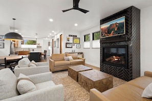 A modern living room with a fireplace, comfortable seating, and a kitchen in the background. - New Listing! Brand New Mountain Modern Home in the Heart of Downtown Creede (Creede)