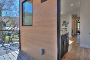 Ein modernes Interieur mit einer Holzwand, einer Glastür, die zu einem Außenbereich führt, und einem Flur mit Holzboden.