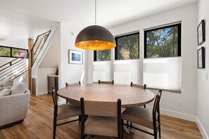 A dining area with a round wooden table and chairs, a modern pendant light, and large windows with blinds. - New Listing! Brand New Mountain Modern Home in the Heart of Downtown Creede (Creede)