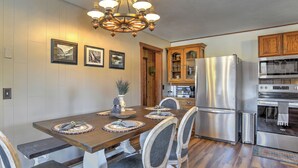 A kitchen with a wooden table, chairs, a refrigerator, oven, and a chandelier. - New Listing! Quiet Mtn Cabin | River and Mtn Views | Expansive Deck (Creede)