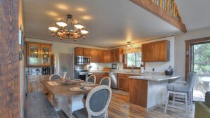 A spacious kitchen with wooden cabinets, a central island, and a dining area with chairs. - New Listing! Quiet Mtn Cabin | River and Mtn Views | Expansive Deck (Creede)