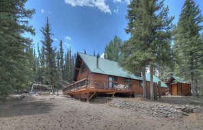 Une cabane dotée d’une terrasse en bois, d’un toit en métal et d’une grande fenêtre.