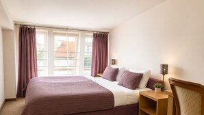 A bedroom with a large bed, a nightstand, a lamp, and a chair. - Hotel Secesja (Kraków)