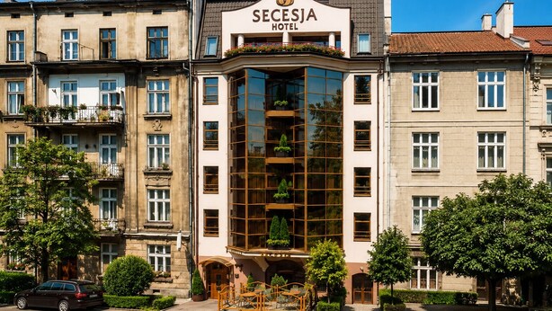 A hotel with a prominent sign, multiple windows, and a balcony with plants. - Hotel Secesja (Kraków)