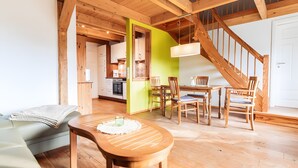 A wooden interior with a dining area, a staircase, and a kitchen. - Holiday Apartment for 4 Guests (60 m²) on Fehmarn (Fehmarn)
