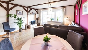 Una sala moderna con un sofá, una mesa de comedor con una planta, un televisor y una estantería.