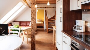 Ein Loftzimmer mit Essbereich, Küchenzeile und einer Treppe zu einer erhöhten Ebene.