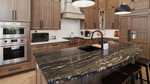 A modern kitchen with wooden cabinets, stainless steel appliances, a marble island, and pendant lighting. - Luxury in Desert Ridge (Phoenix)
