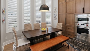 A kitchen with a dark wooden table, wicker chairs, a bench, and a hanging pendant light. - Luxury in Desert Ridge (Phoenix)