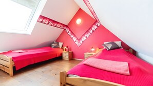 Un dormitorio con dos camas, piso de madera y techo inclinado con tragaluz.