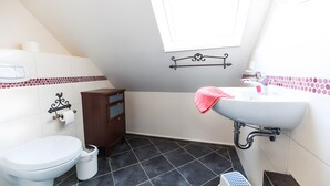 Un baño con inodoro, lavamanos, armario y zona de ducha.