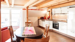 Una cocina moderna con armarios blancos, una mesa de comedor de madera con sillas y un microondas rojo.