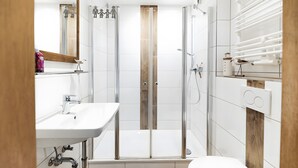Une salle de bain moderne avec une douche à parois de verre, un lavabo blanc et un miroir.