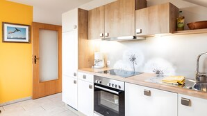 Une cuisine moderne avec des meubles en bois, un four encastré, une machine à café et un évier.