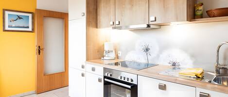 A modern kitchen with wooden cabinets, a built-in oven, a coffee maker, and a sink.