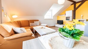 Un appartement moderne de style « loft » comprenant un canapé, une table basse, un téléviseur et un coin cuisine.