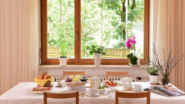 A breakfast table set with various food items and a window with plants. - Double Room with Bathroom and Balcony, Mountain View (Merano)