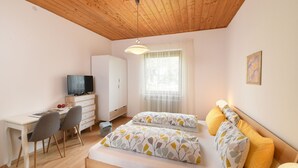 Une chambre à coucher avec un lit, un bureau, une chaise, une télévision et une fenêtre.