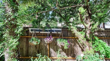 A wooden fence with a hanging planter and a bird feeder.