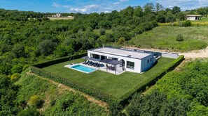 Ein modernes Haus mit Swimmingpool, umgeben von üppigem Grün.