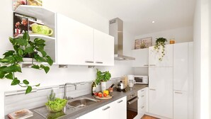 A modern kitchen with white cabinetry, a stainless steel sink, a microwave, and a built-in oven. - Villa Thaler Apartment with Mountain View and Rooftop Terrace (Merano)