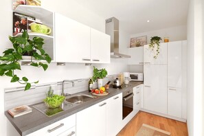 A modern kitchen with white cabinetry, a stainless steel sink, a microwave, and a built-in oven. - Villa Thaler Apartment with Mountain View and Rooftop Terrace (Merano)
