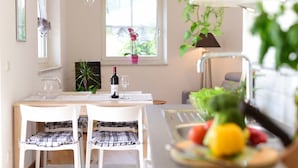 A dining area with a table, chairs, a bottle of wine, and a fruit bowl. - Villa Thaler Apartment with Mountain View and Rooftop Terrace (Merano)
