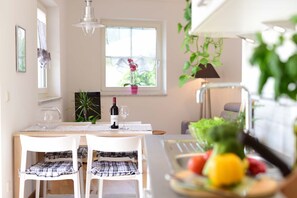 A dining area with a table, chairs, a bottle of wine, and a fruit bowl. - Villa Thaler Apartment with Mountain View and Rooftop Terrace (Merano)