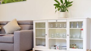 A living room with a grey sofa, a white cabinet with glass doors, and a potted plant on top. - Villa Thaler Apartment with Mountain View and Rooftop Terrace (Merano)