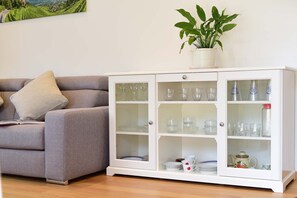 A living room with a grey sofa, a white cabinet with glass doors, and a potted plant on top. - Villa Thaler Apartment with Mountain View and Rooftop Terrace (Merano)