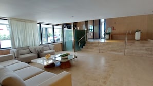 A modern living room with a sofa, coffee table, and a staircase leading to an upper level. - COSTE0112 - Premium Stella Maris (Salvador)