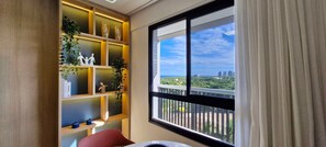 Ein Zimmer mit einem großen Fenster, einem Holzboden mit Dekoration und einem roten Sessel.