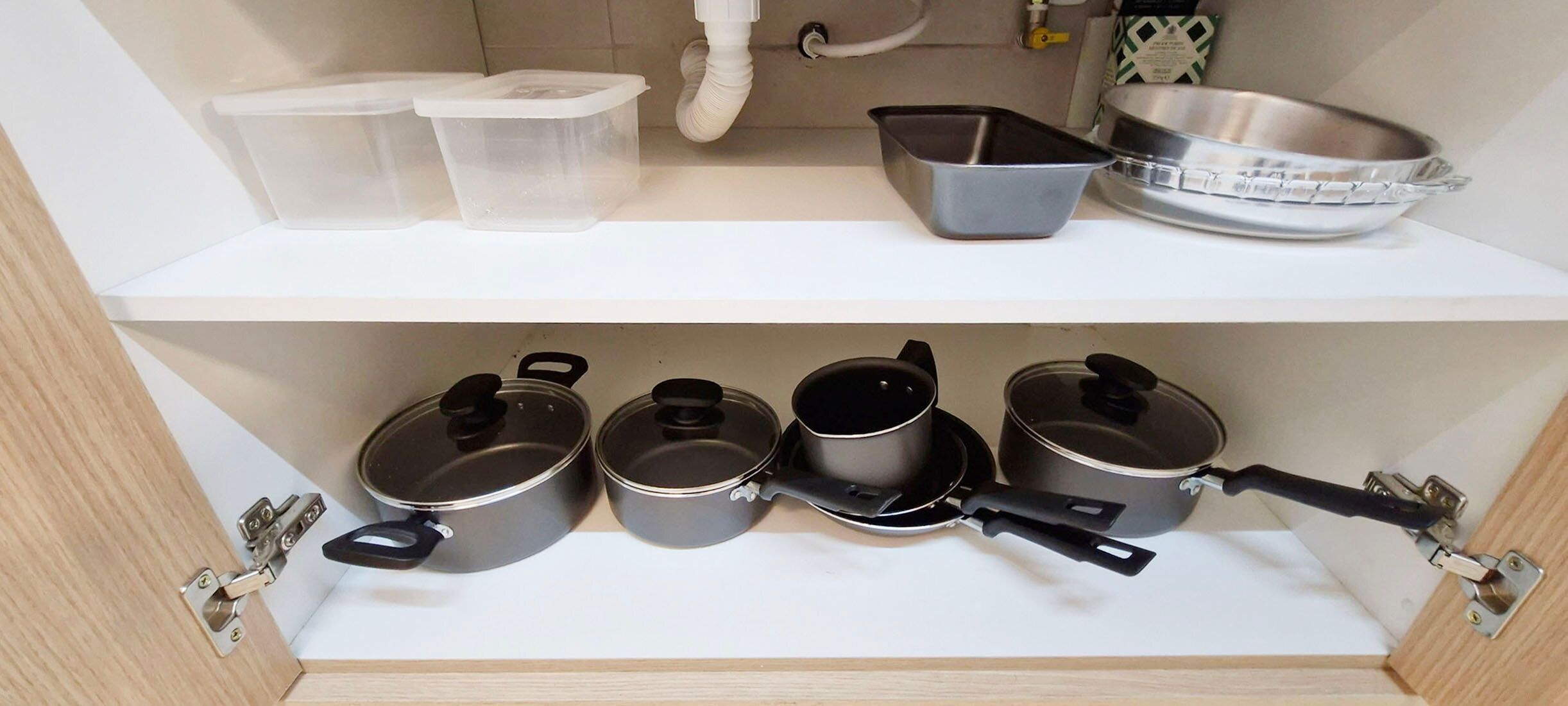 Une cuisine équipée de boîtes de rangement, de casseroles et d’un saladier en métal posé sur le plan de travail.