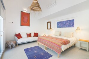 A bedroom with a bed, two sofas, a rug, and artwork on the walls.