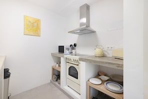 Una cocina compacta con estufa, horno y una campana extractora moderna.
