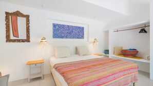A bedroom with a bed, a nightstand, a wall-mounted artwork, a hanging light fixture, and a shelf with a basket. - Wellness Garden Cottage with Yoga, Pilates and Natural Pond (Moncarapacho)