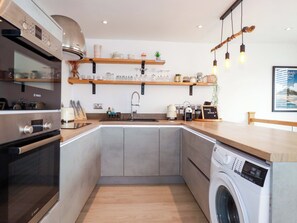 Uma cozinha compacta com forno Bosch, máquina de lavar e cafeteira.